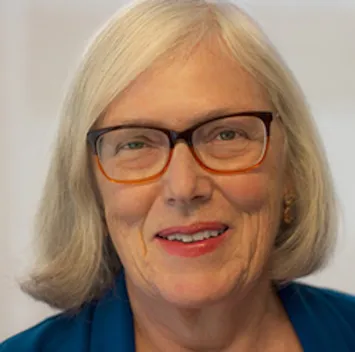 Older woman with gray hair wearing glasses and blue jacket