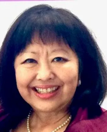 Smiling woman with dark hair and pearl necklace